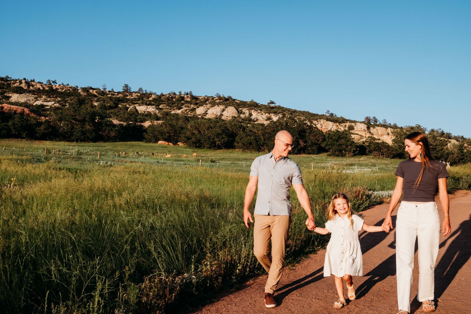 South Valley Park Mini Session with family of three - Denver Photographer, family walking on trailhead path in full sun with blue skies.