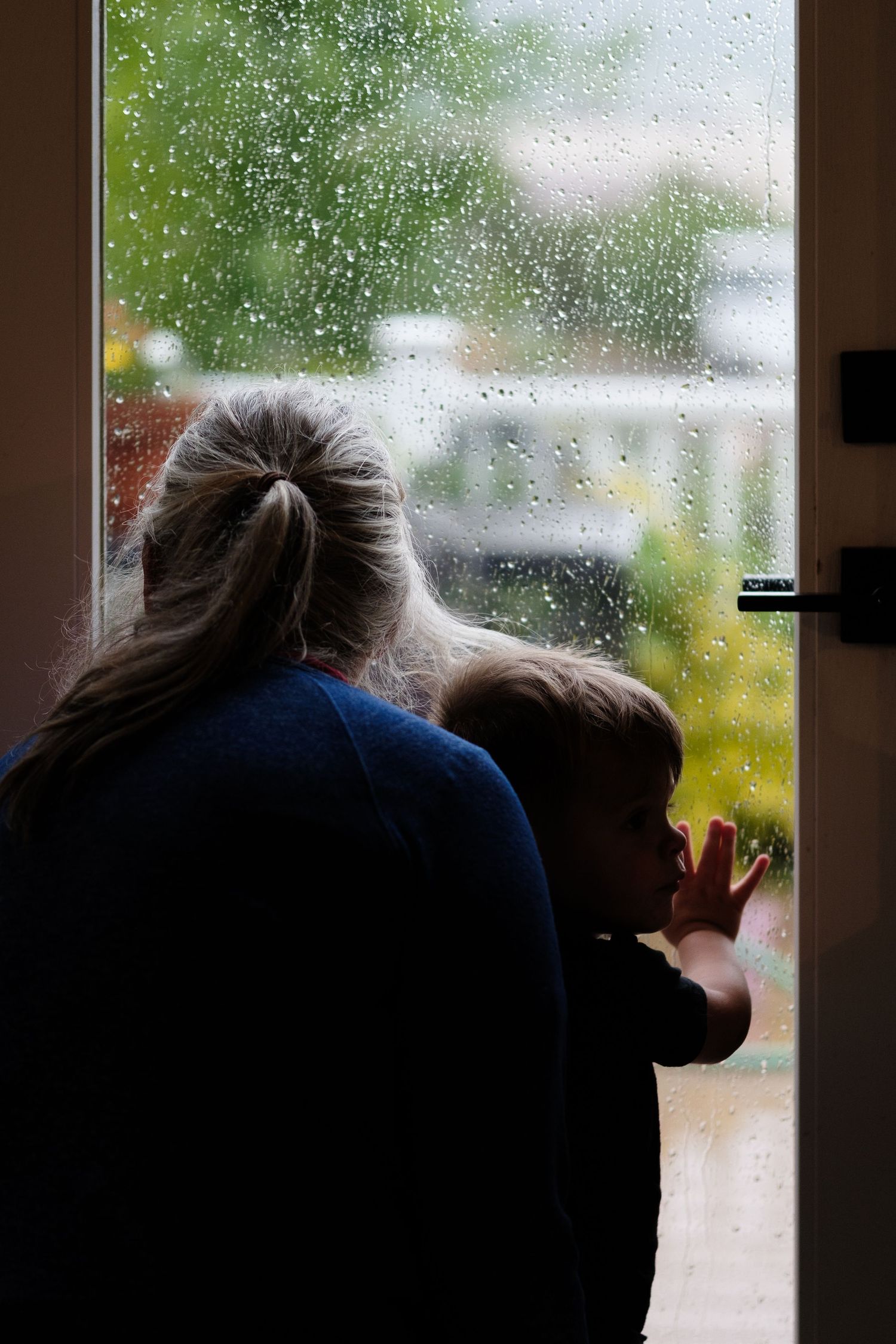 Denver photographer's project 365, May, silhouette of grandmother and grandson looking out glass door window and rainy day.