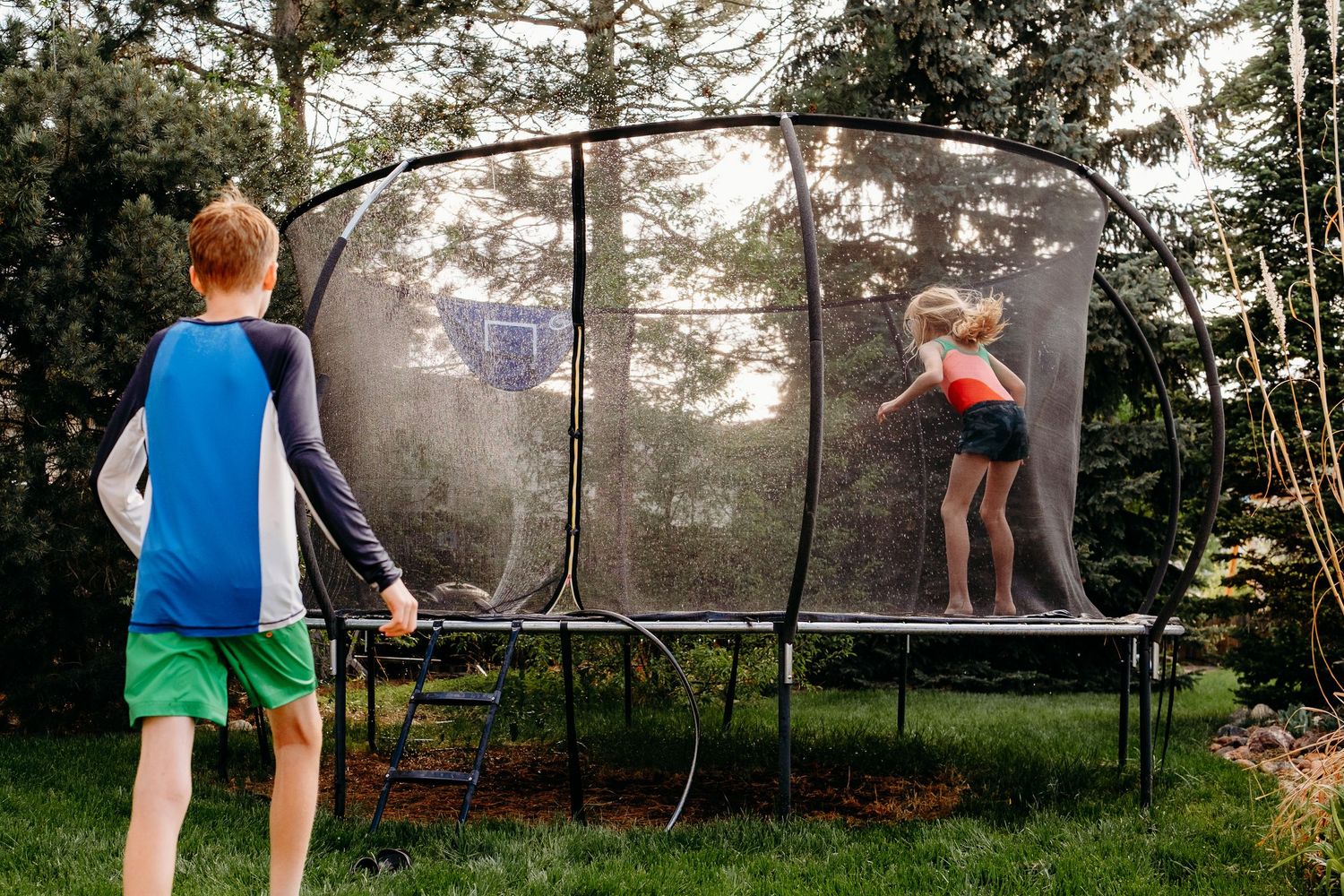 Denver photographer's project 365, May, two children playing in backyard wearing swimsuits, one jumping on a trampoline.