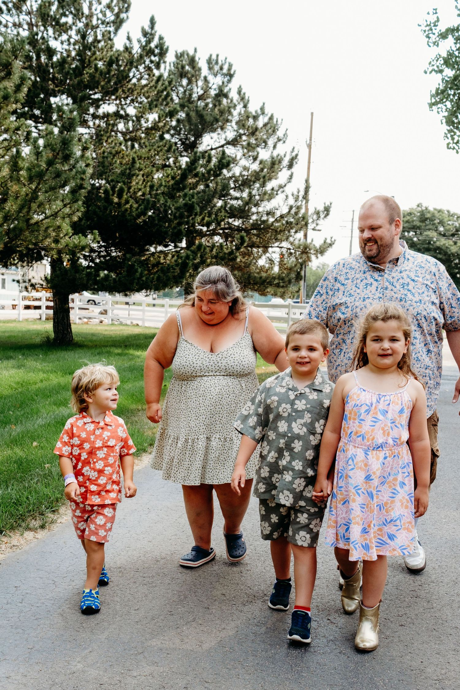 Playful walking portrait of three and their parents walking behind them on family property.