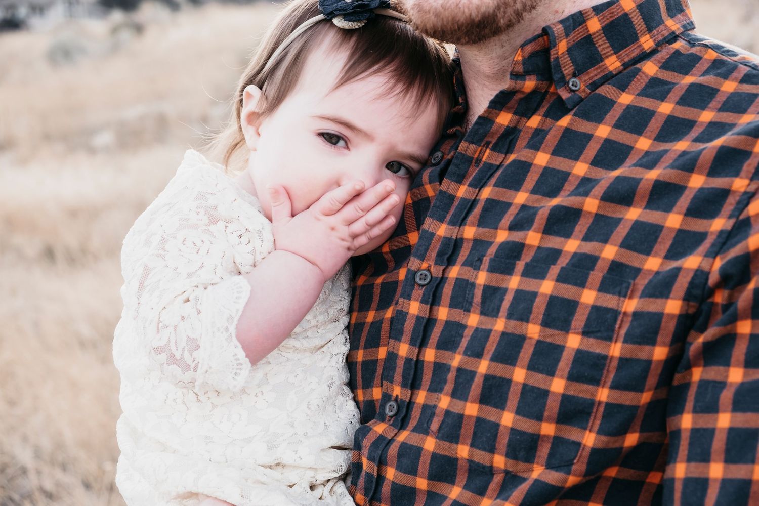 Young girl blowing kisses while snuggled closely to dad's chest at Mount Falcon East in Morrison, Colorado.