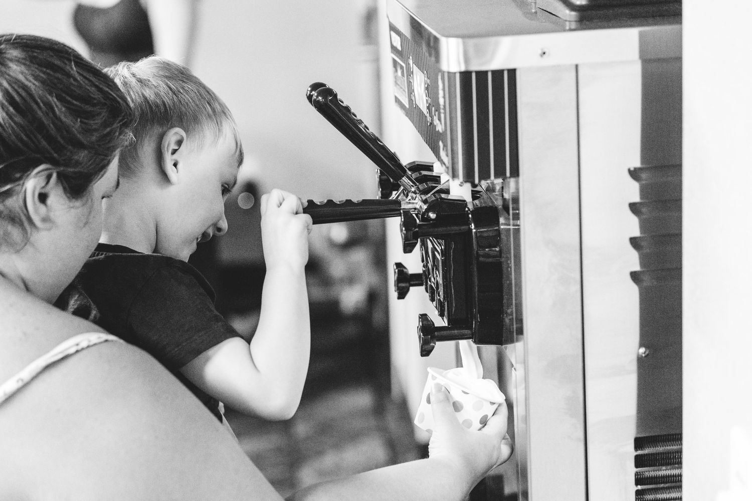 Aunt helping nephew dispense ice cream maker to serve up soft serve ice cream at grandma's 90th birthday party.
