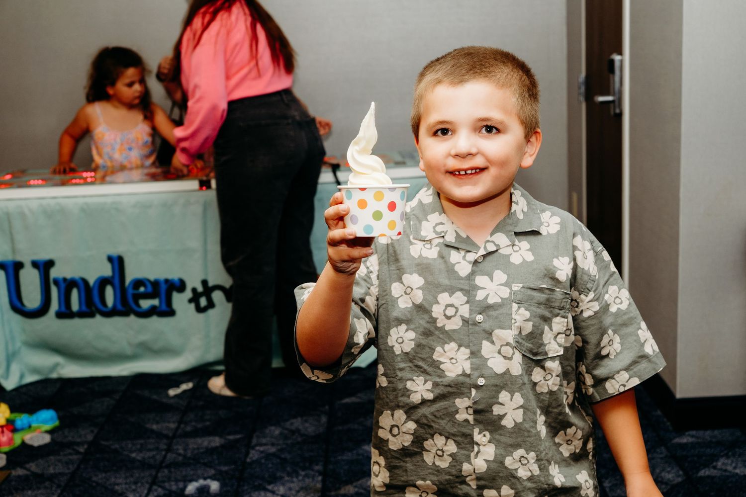 Young boy holding cup of soft serve ice cream cone.