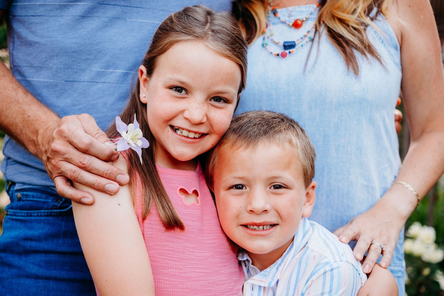 Close up of brother and sister, both smiling, mother and father standing behidn them.