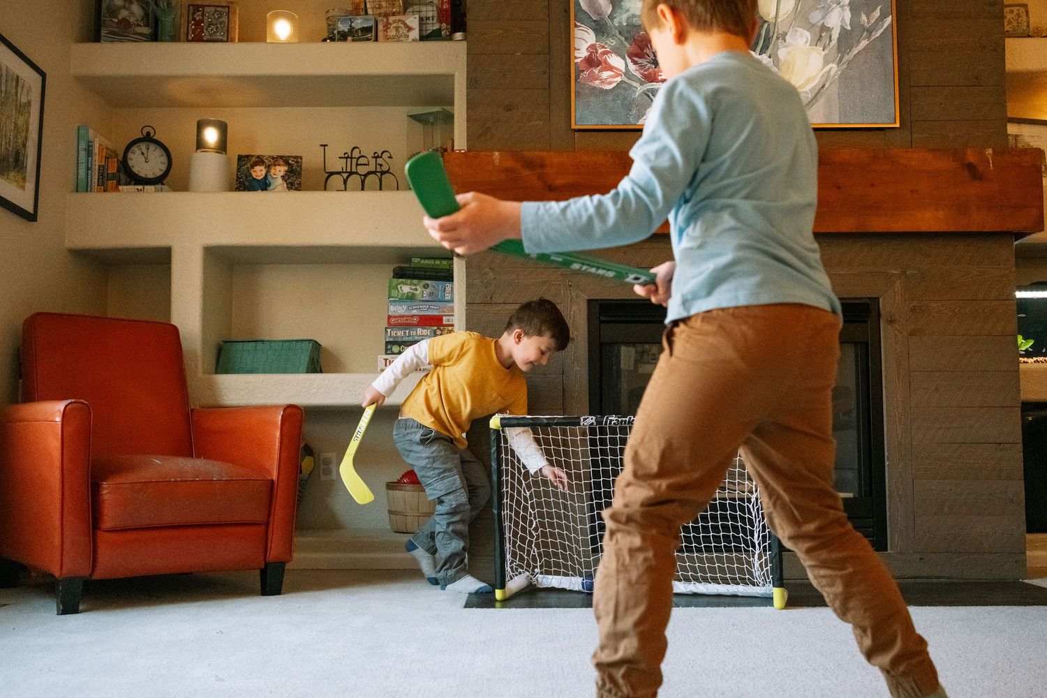 Two brothers playing living room hockey during in home documentary family photography session.