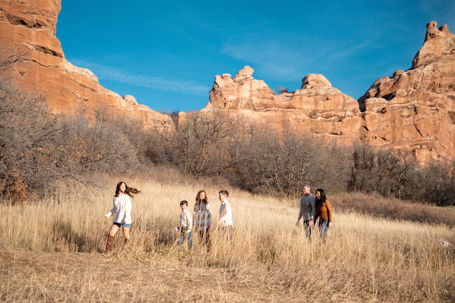 Denver family walking in front of stunning rock formation and blue skies at South Valley Park.