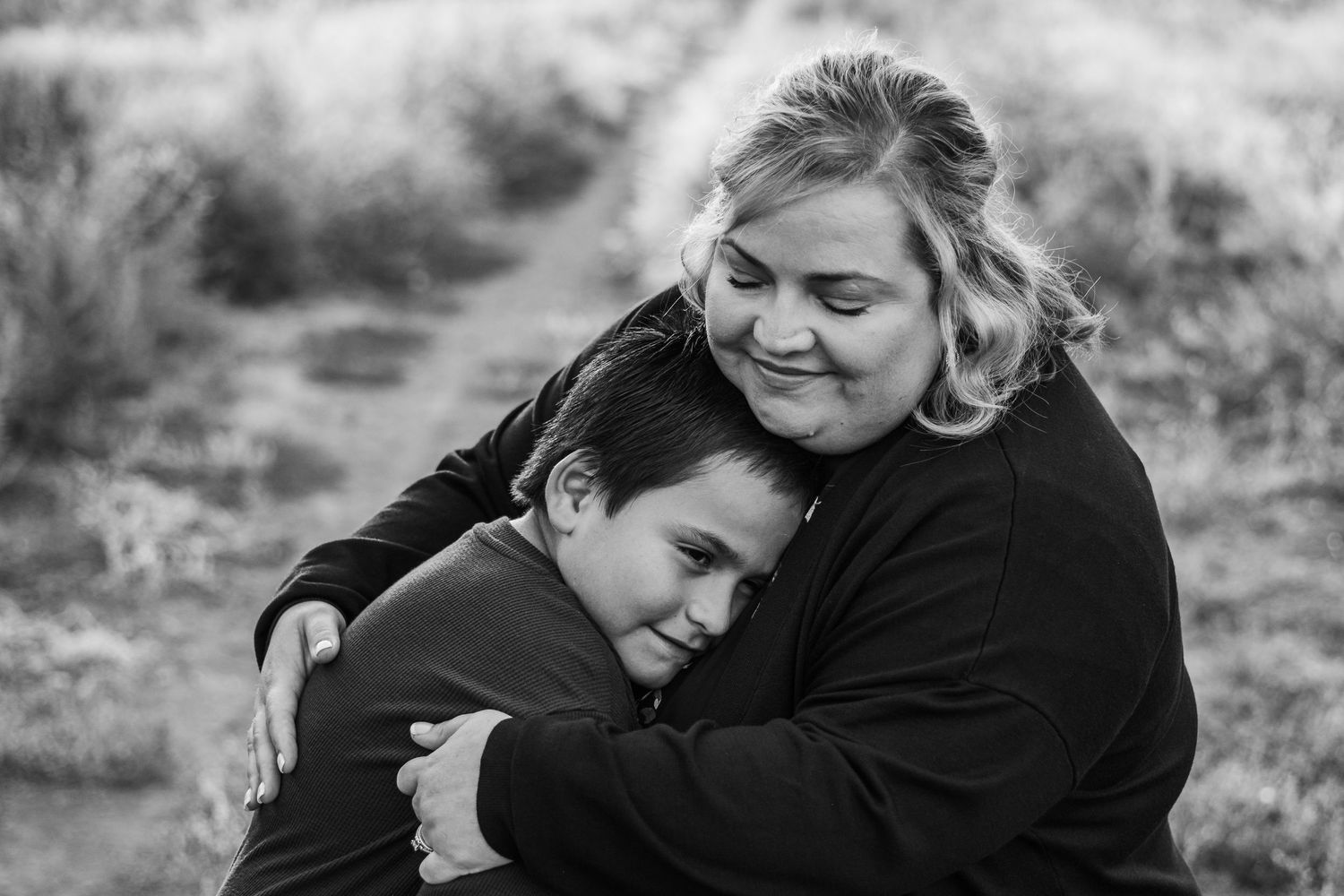 Black and white of mother snuggling son in field at Bear Creek Lake Park.