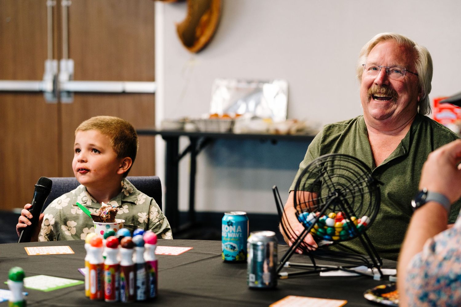 Grandfather and grandson sitting at table, laughing.