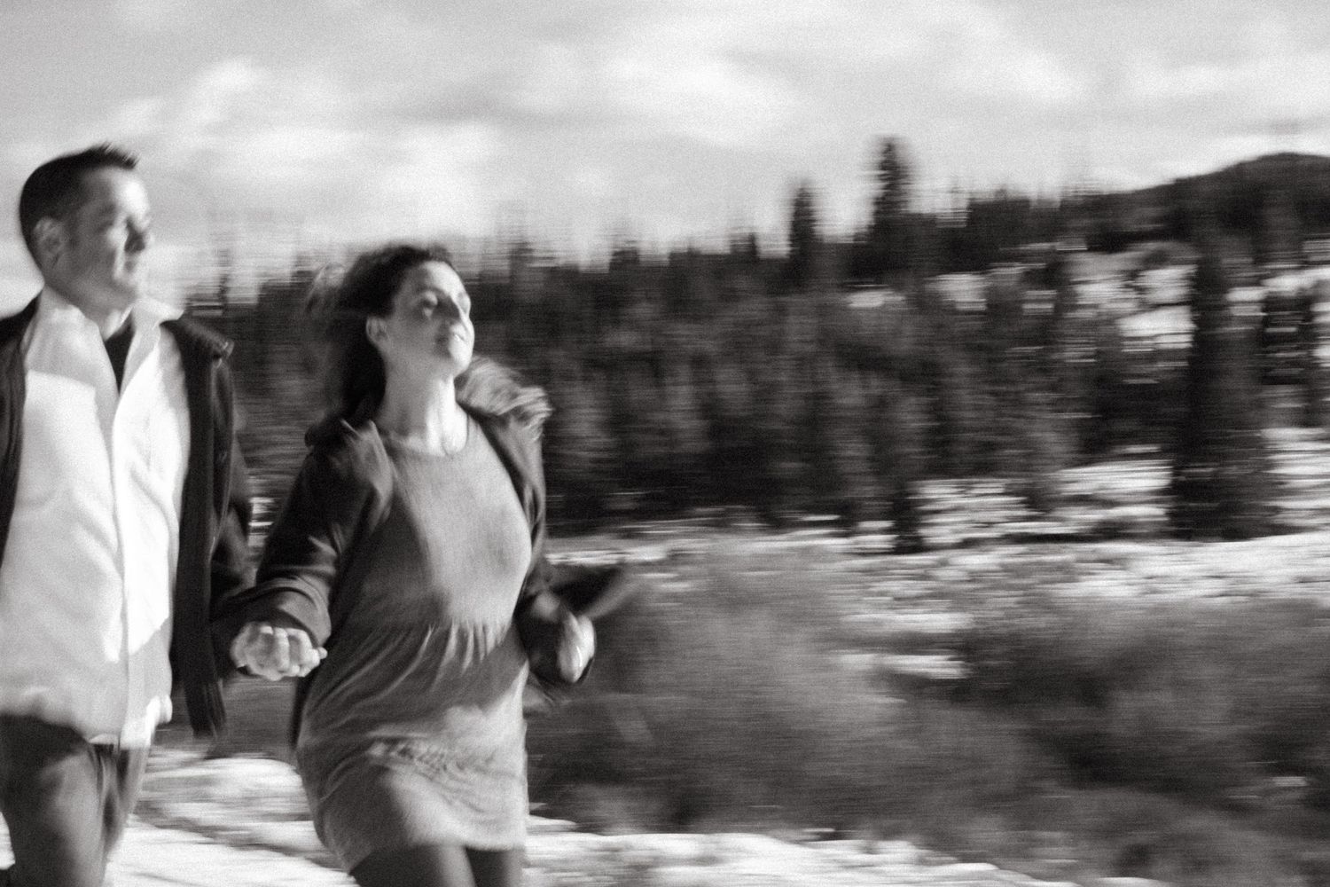 Artistic style black and white portrait of newly engaged couple running, with intentional motion blur near Breckenridge, Colorado.