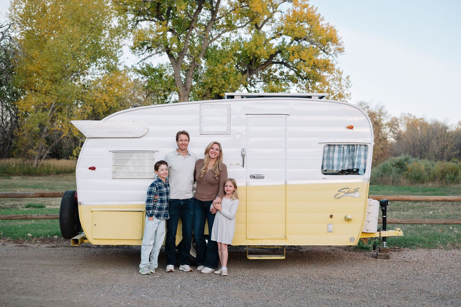 Family of mother, father and two children in front of vintage Shasta trailer at Bear Creek Lake Park in Lakewood, Colorado.