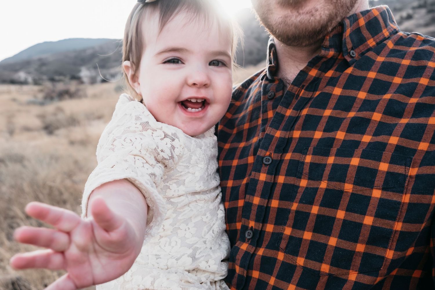 Close up of baby girl smiling while being held by dad.
