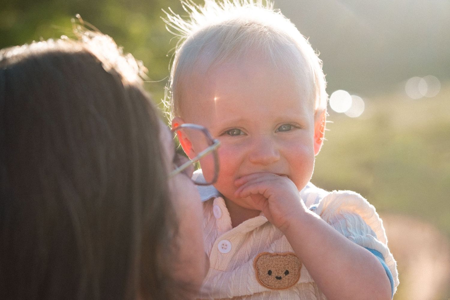 Mother holding one year old son closely, golden light backlighting both of them at South Valley Park in Littleton, Colorado.