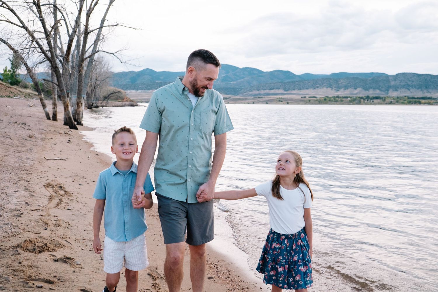 Father walking with daughter and son along shoreline at Chatfield reservoir.