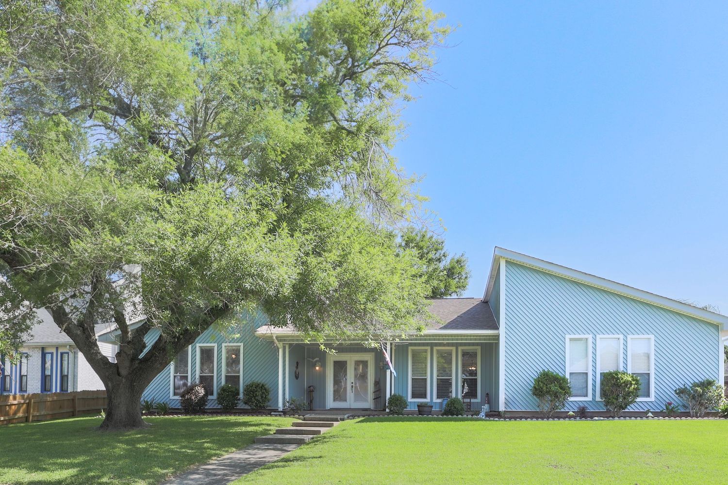 A panoramic sequence showing a grassy hillside with trees and white residential buildings under a blue sky.