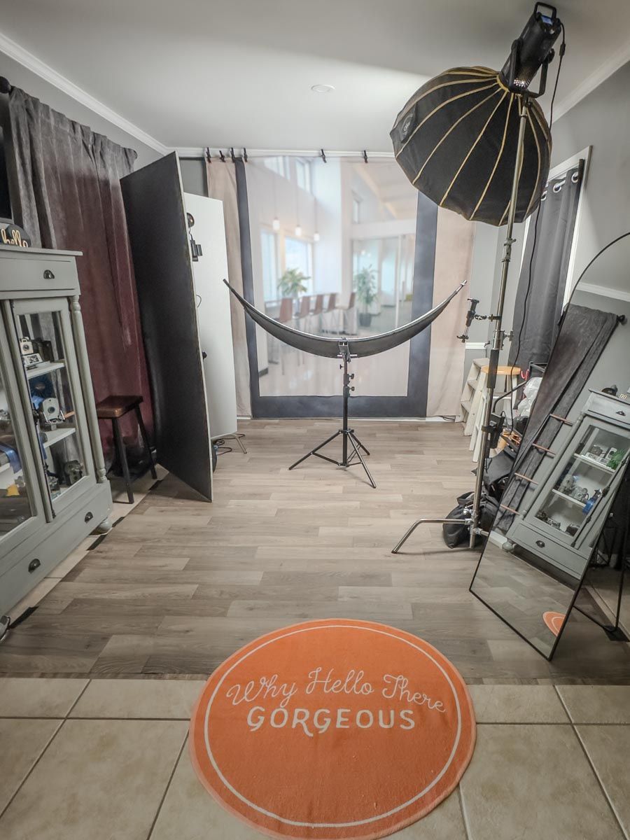 A photography studio setup with lighting equipment and three orange circular floor mats displaying encouraging messages.