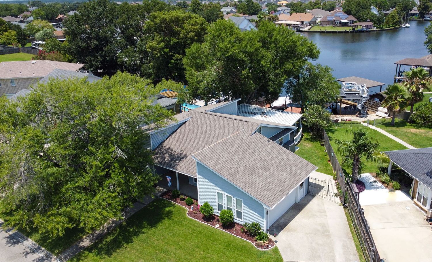Aerial view of waterfront home with boat dock and lush landscaping on sunny Florida canal.