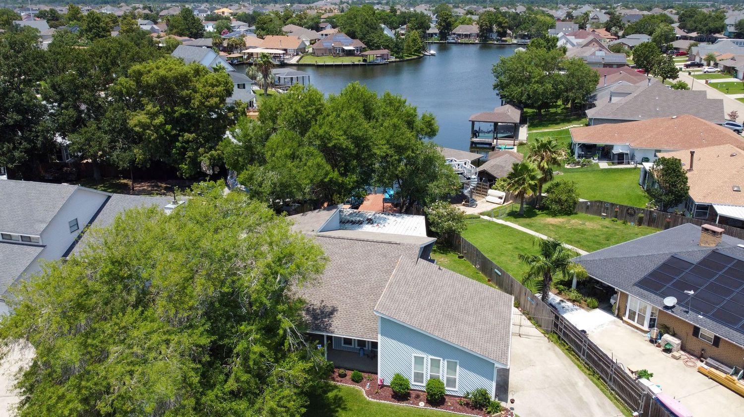 Aerial view of waterfront residential homes with private docks along a canal surrounded by lush trees in Florida.