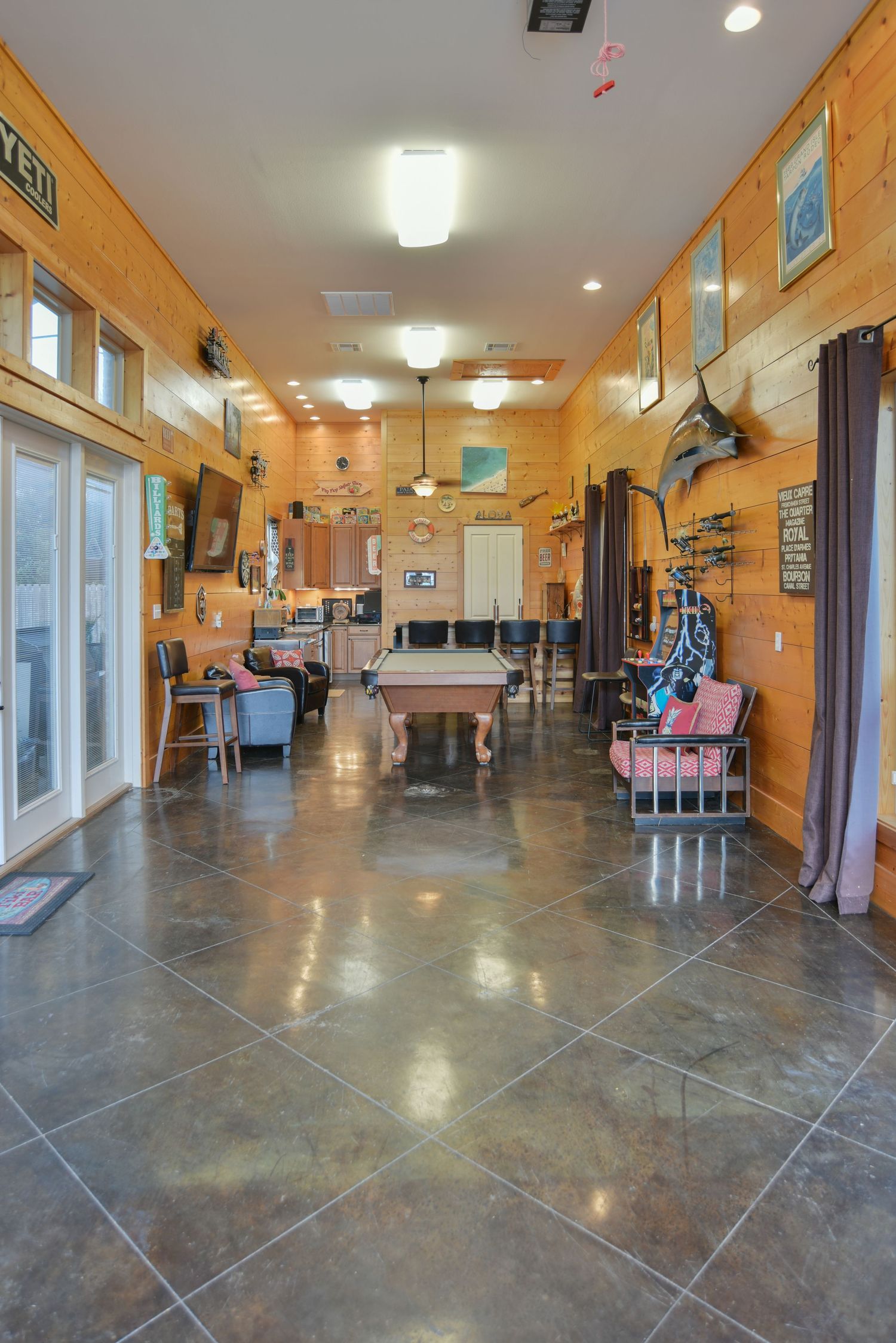 Interior view of a rustic salon with wooden paneled walls, polished concrete floors, and salon chairs lined along the walls.