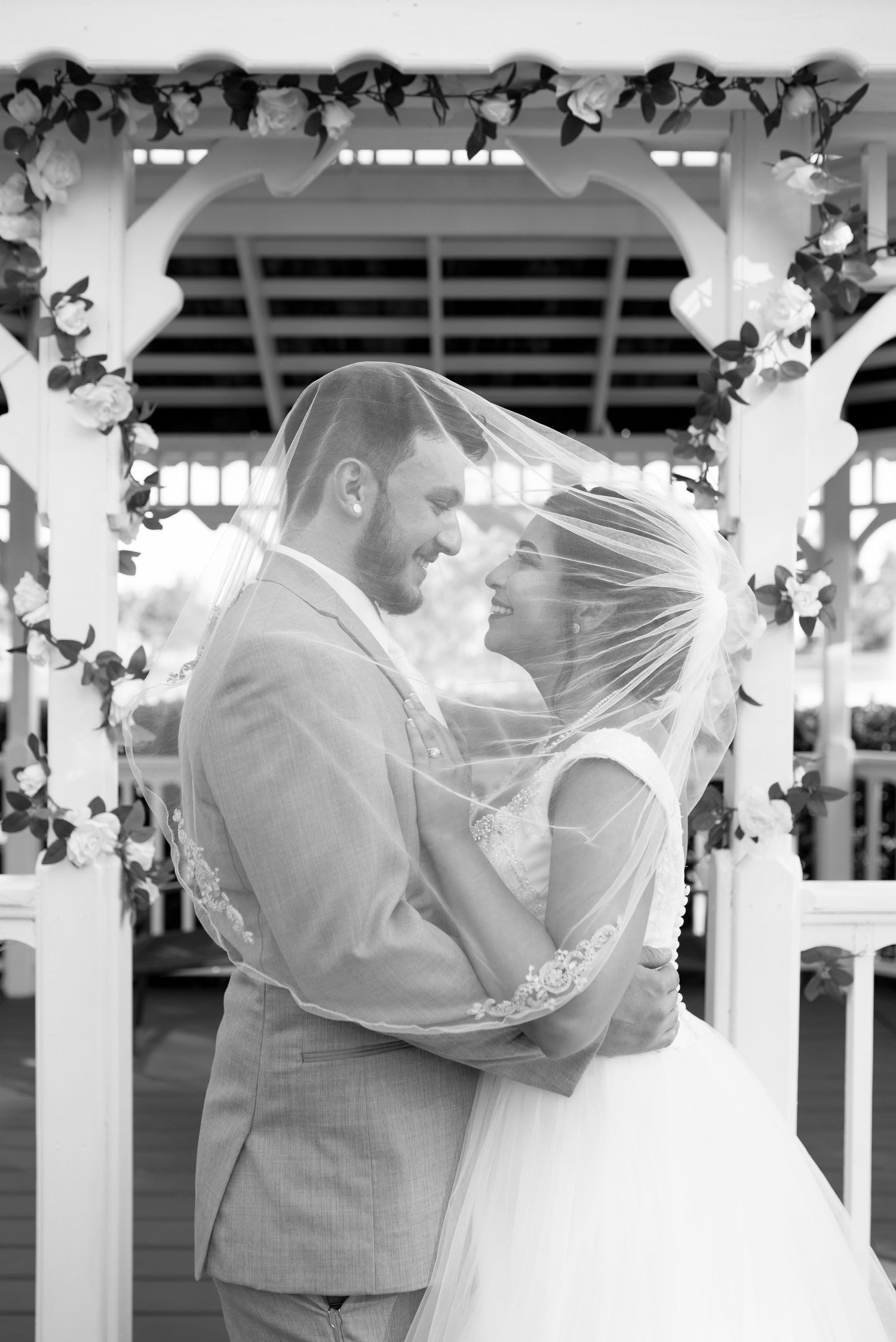 Wedding couple sharing an intimate moment under a decorated white gazebo.