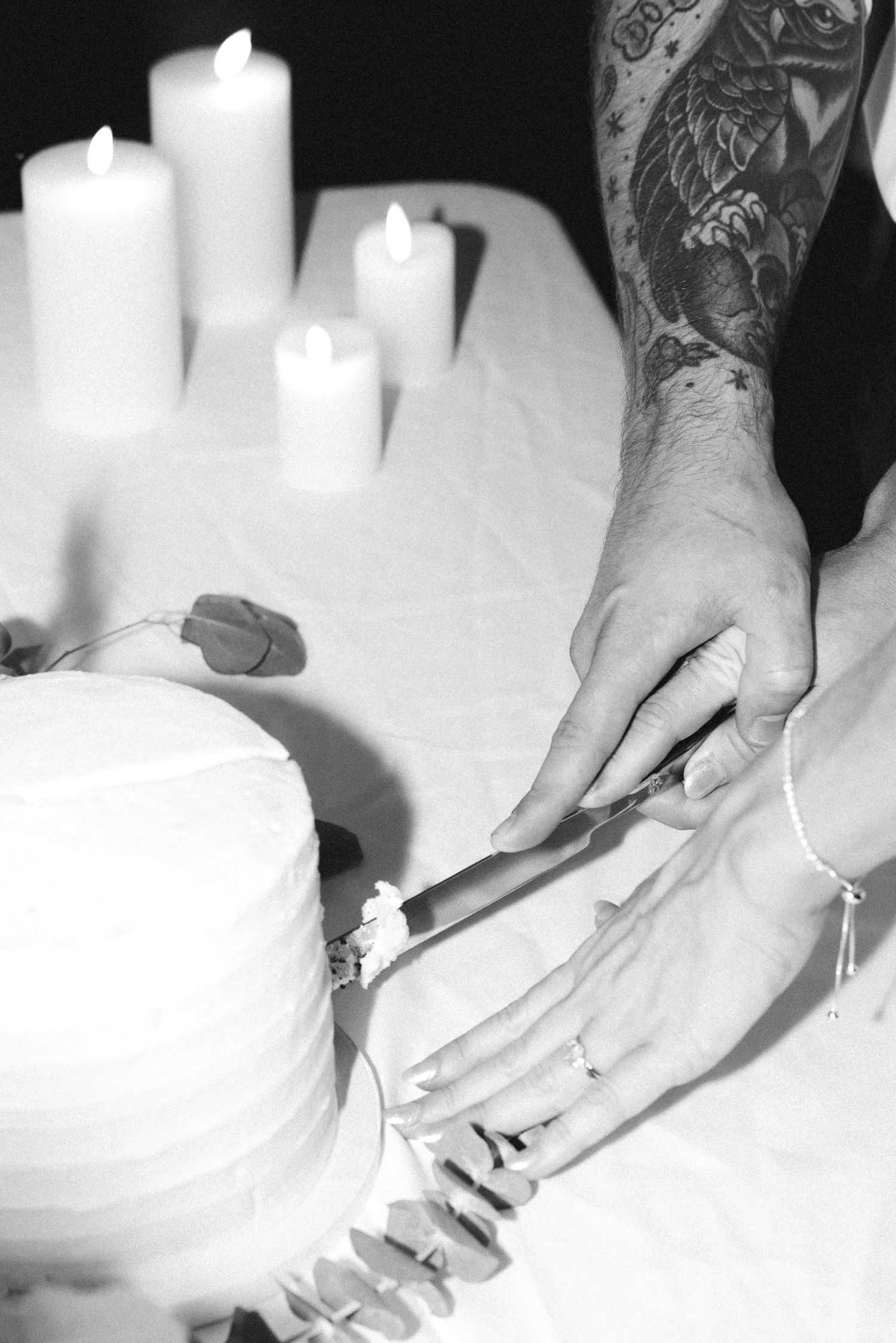 Close-up shots of hands cutting into a white wedding cake.