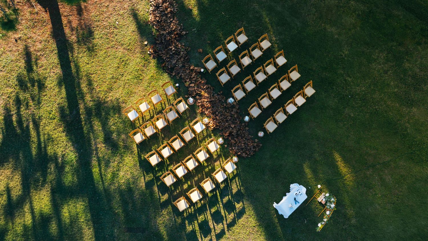Aerial view of outdoor wedding ceremony seating arrangement on a grassy lawn.