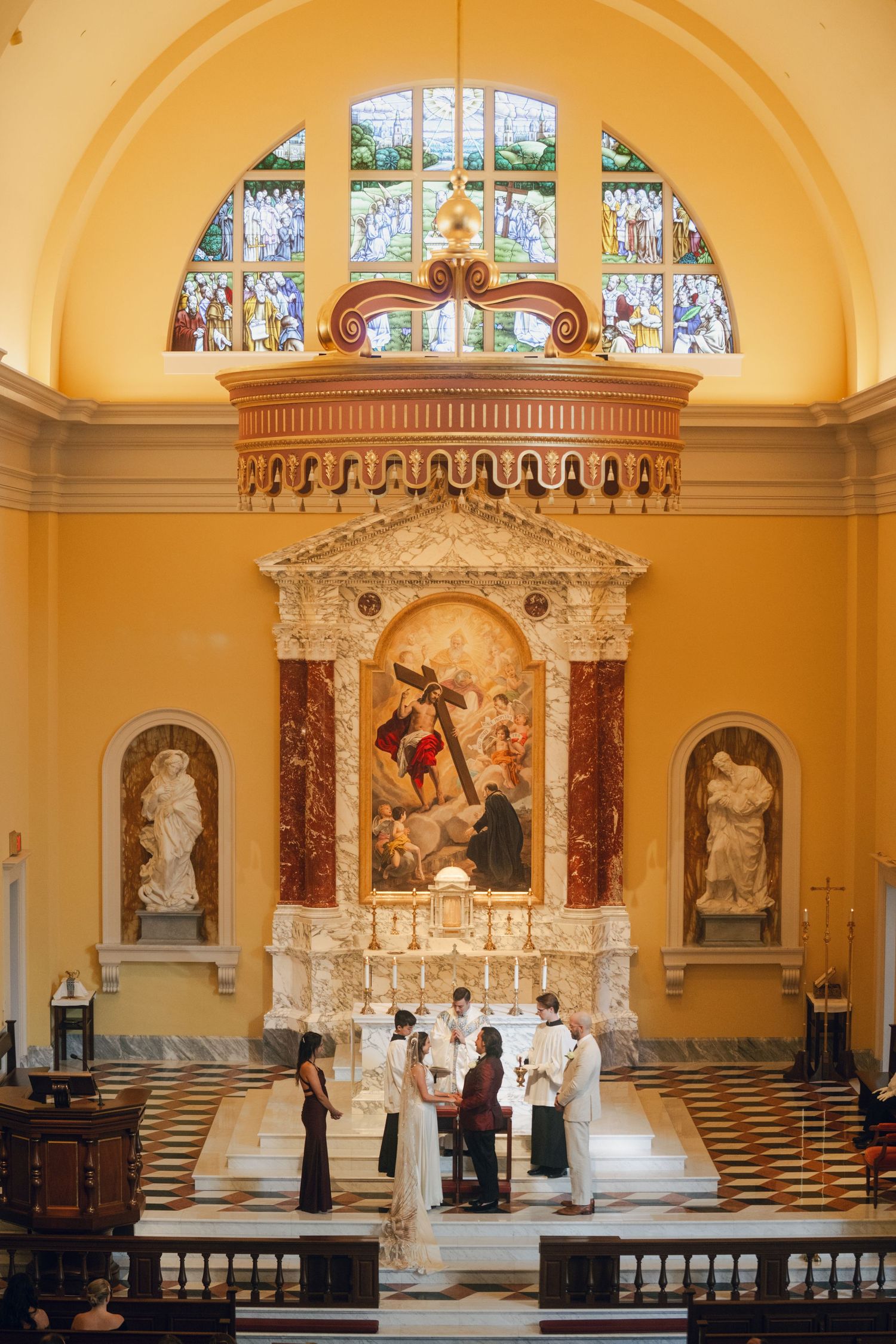 Beautiful church sanctuary with golden walls, marble statues and decorative altar.