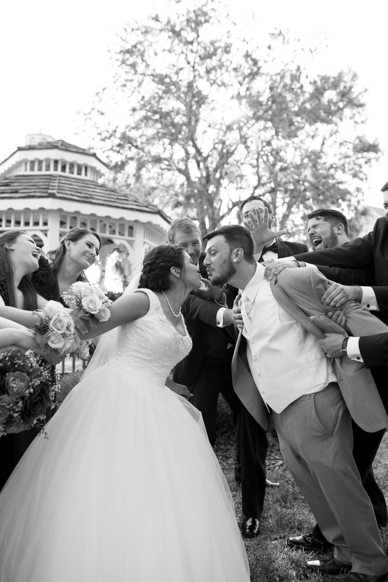 Playful wedding party strikes dramatic poses during outdoor photo session.