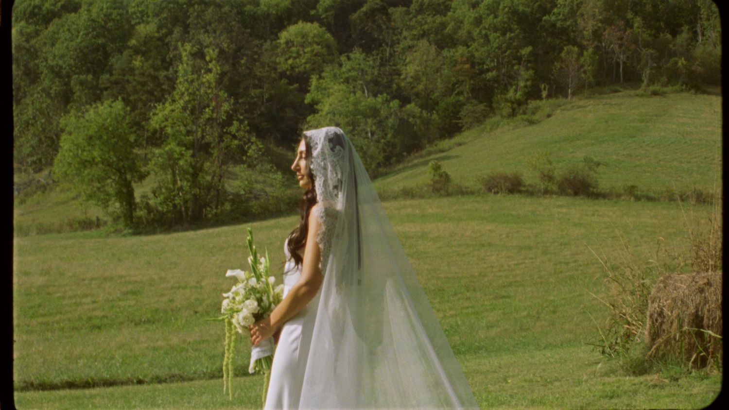 Rolling green hillside with a figure in white holding a bouquet.