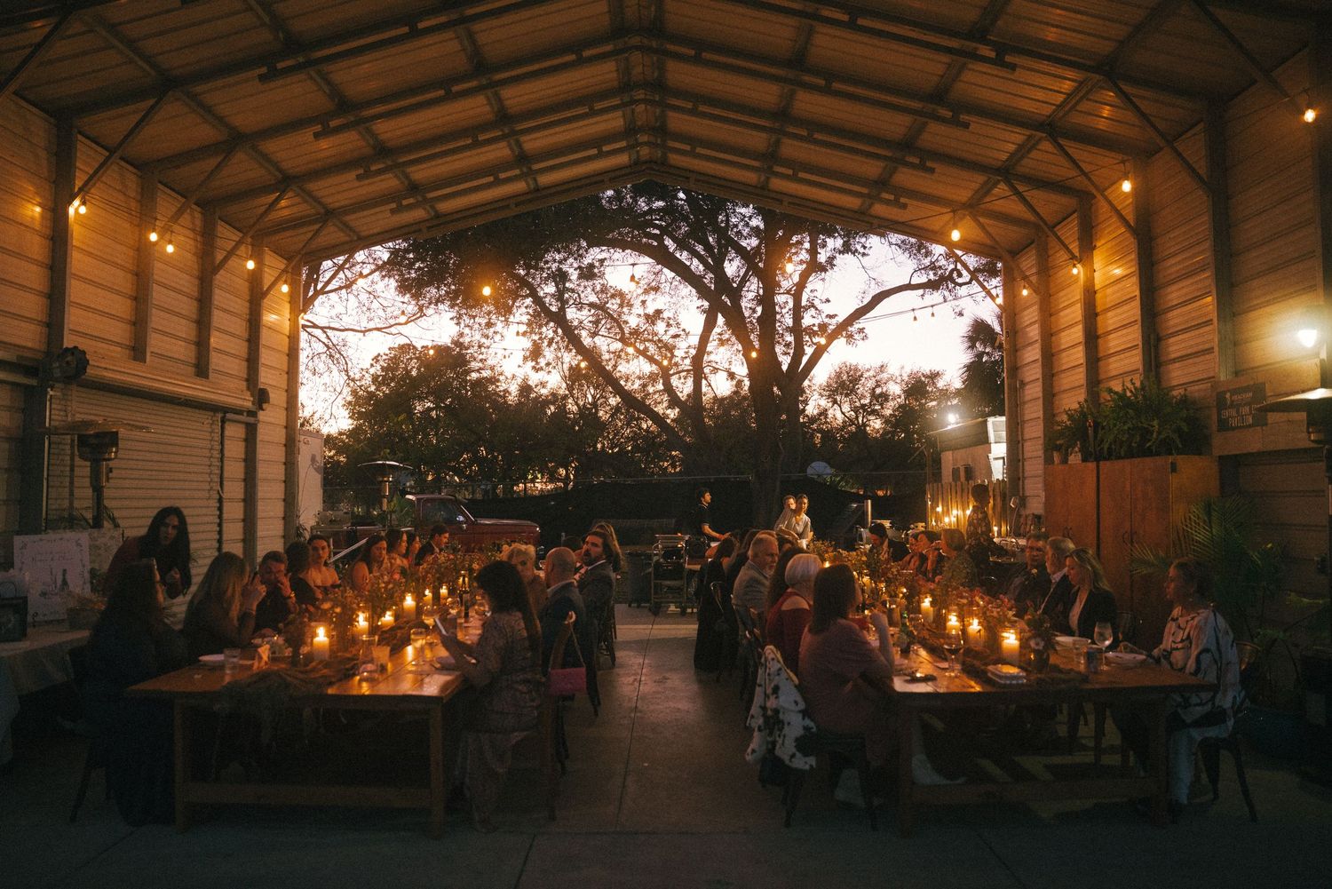 Outdoor wedding reception venue at dusk with string lights creating a warm ambiance.
