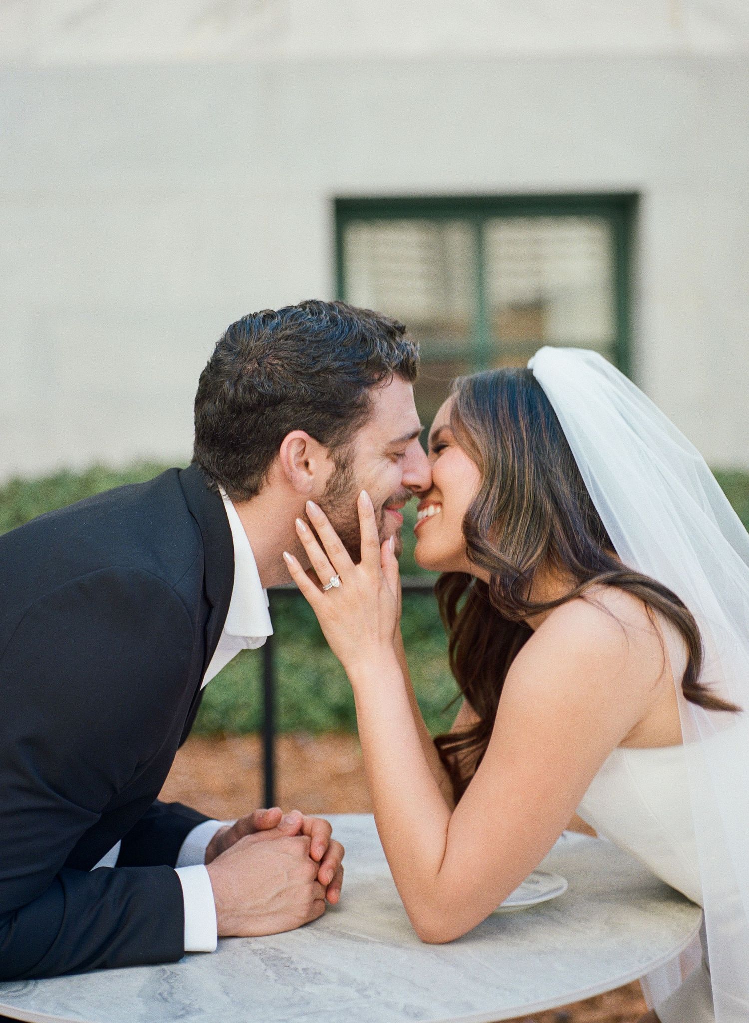 Playful wedding couple lying on marble ledge.