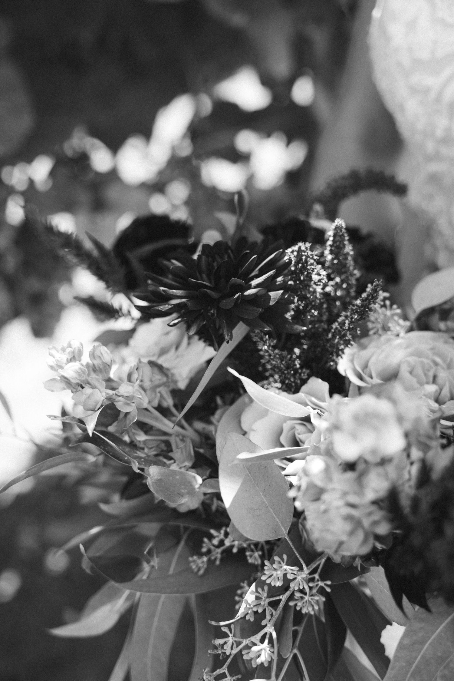 Black and white close-up of an elegant wedding bouquet with mixed flowers and greenery.