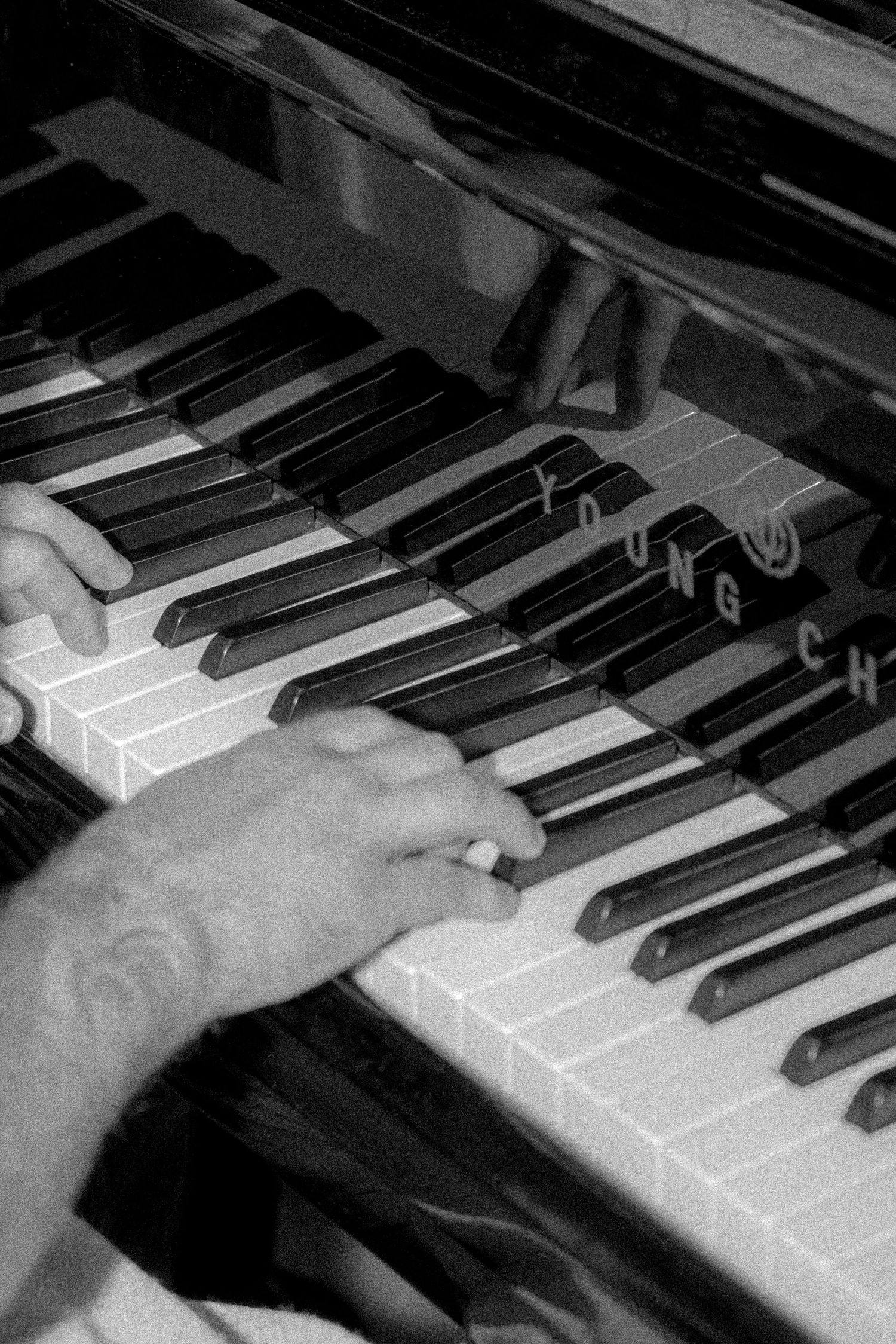 Black and white close-up of hands playing piano keys.