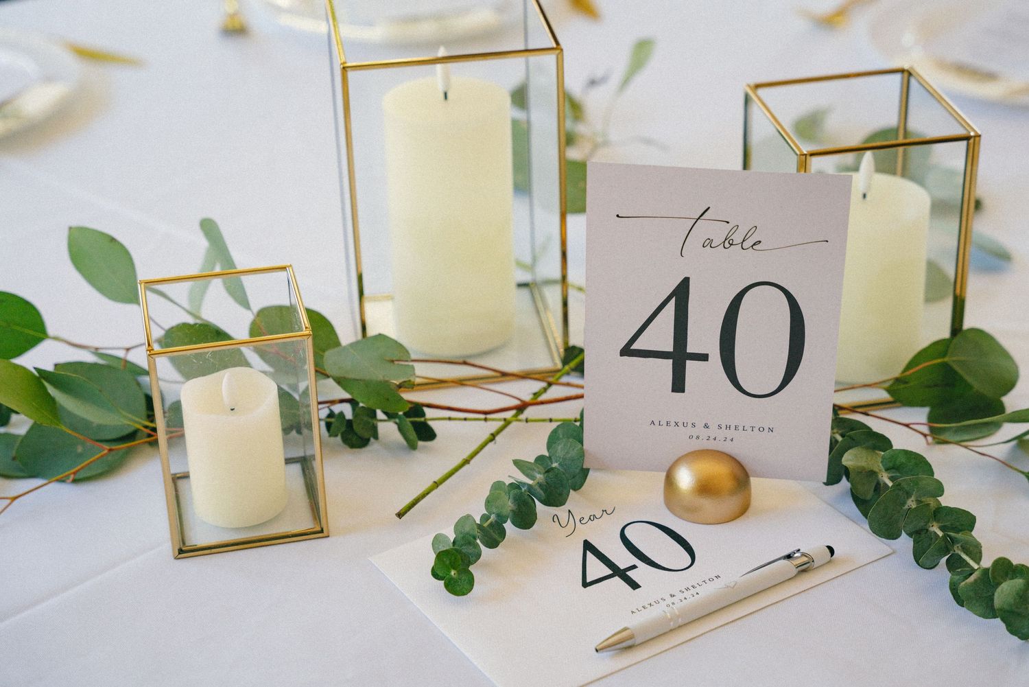 Elegant table setting with geometric lanterns, eucalyptus sprigs, and table number forty card.