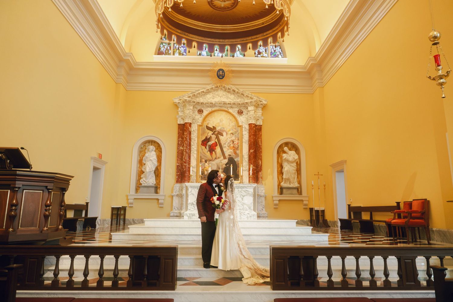 Interior view of a traditional Catholic church with yellow walls and vaulted ceilings.