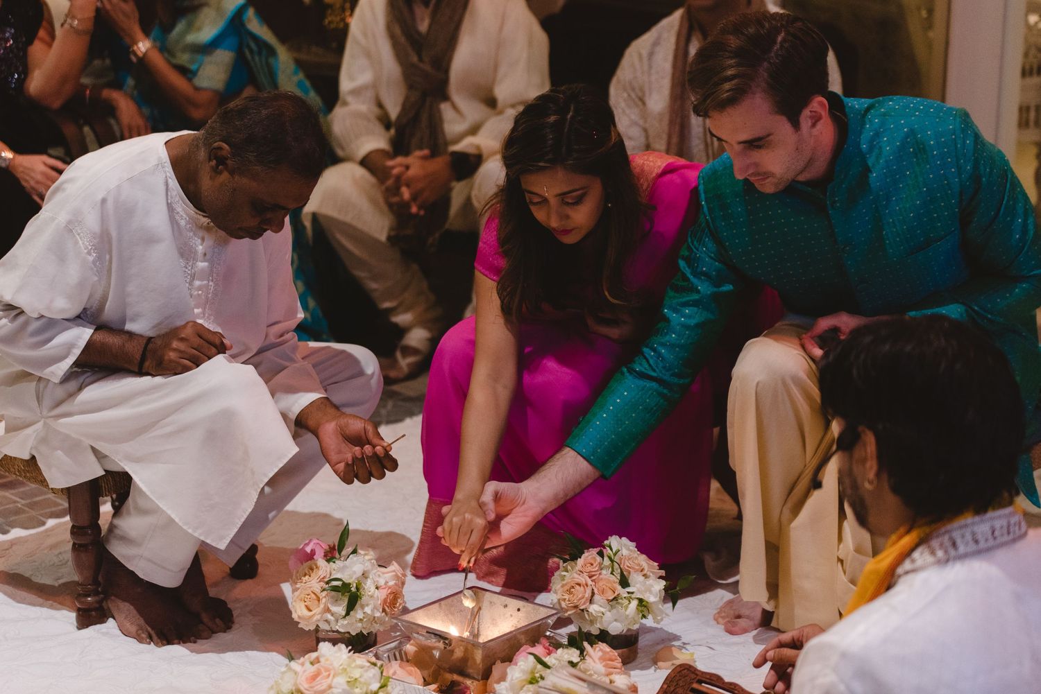 Wedding guests gather around tables at an indoor reception celebration.