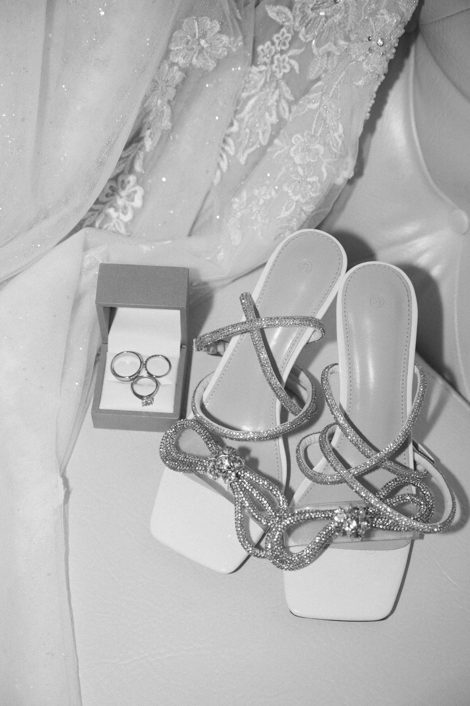 Wedding accessories including sparkly shoes and jewelry arranged on white fabric.
