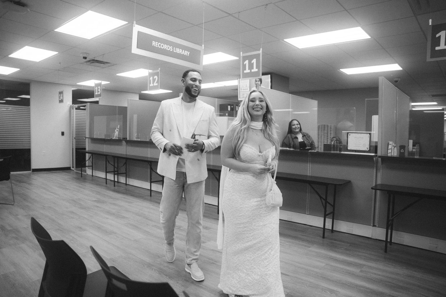 Black and white photo of a couple in wedding attire celebrating inside a courthouse after their civil marriage ceremony.