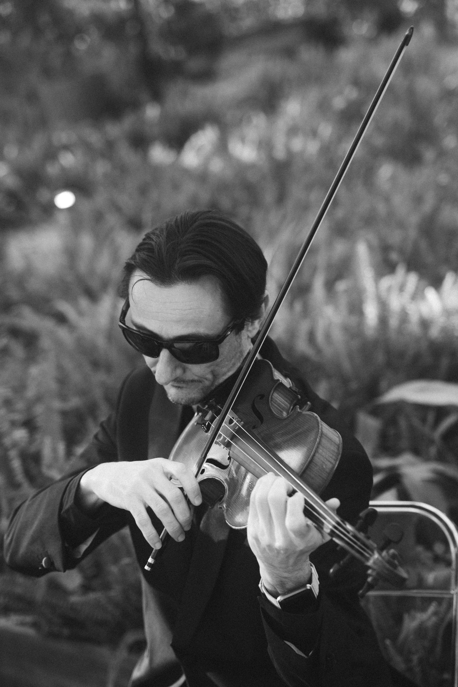A musician plays violin in dramatic black and white photography.
