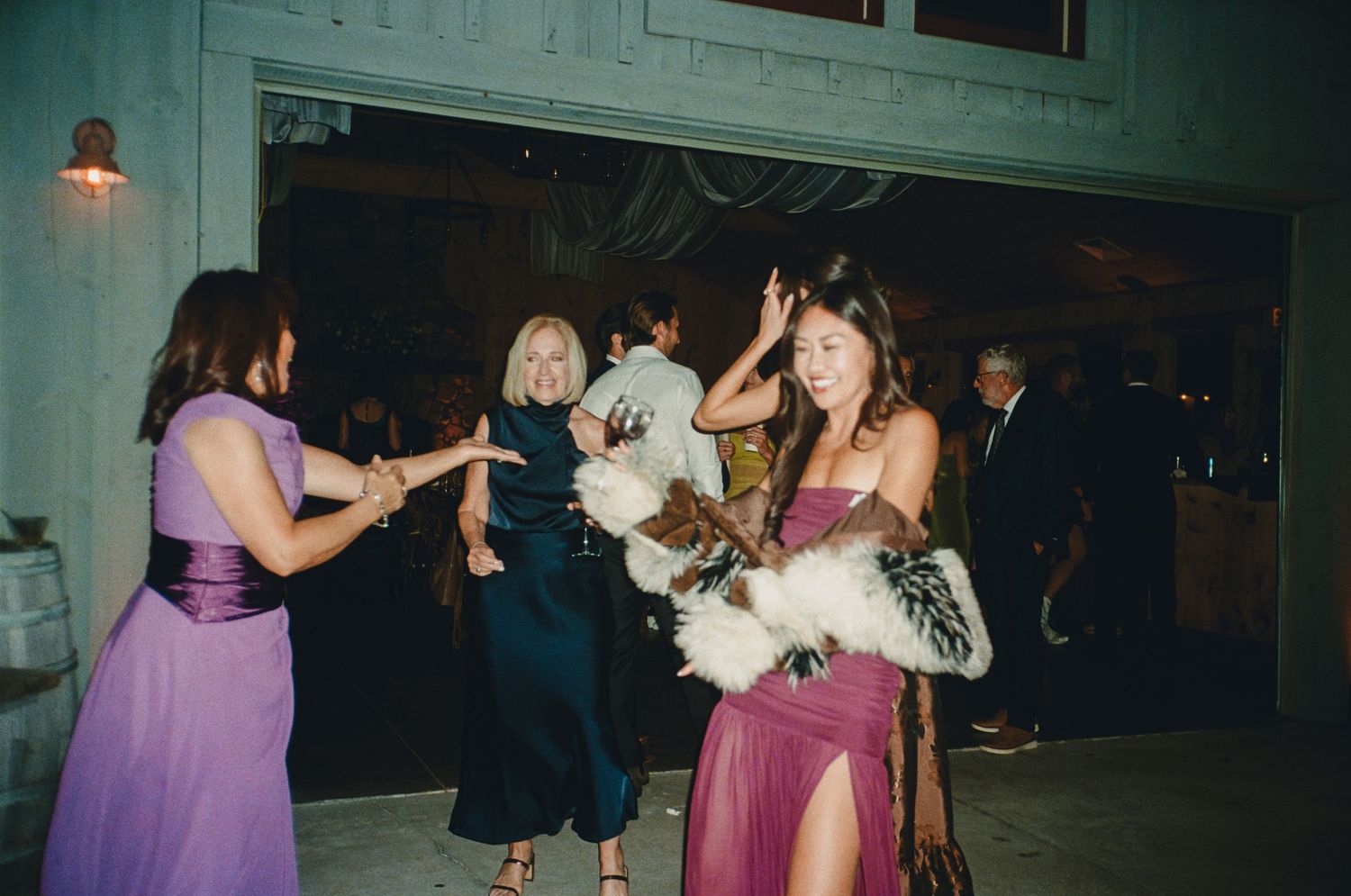 Guests dancing at a wedding reception, wearing elegant gowns and feather accessories.