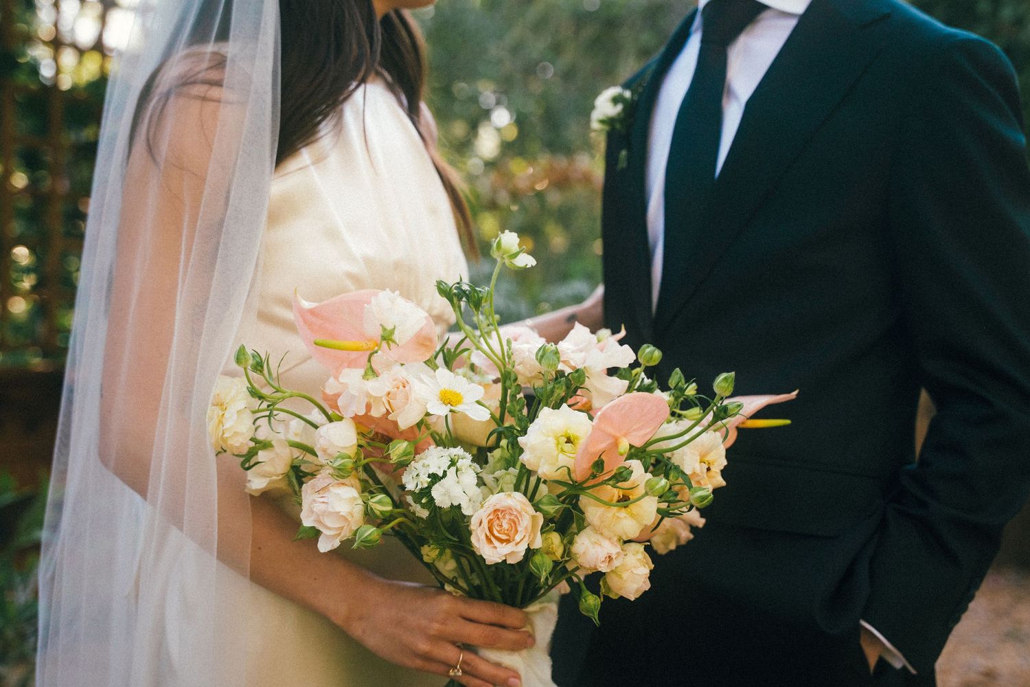 Elegant wedding bouquet with peach roses and white flowers against formal attire.