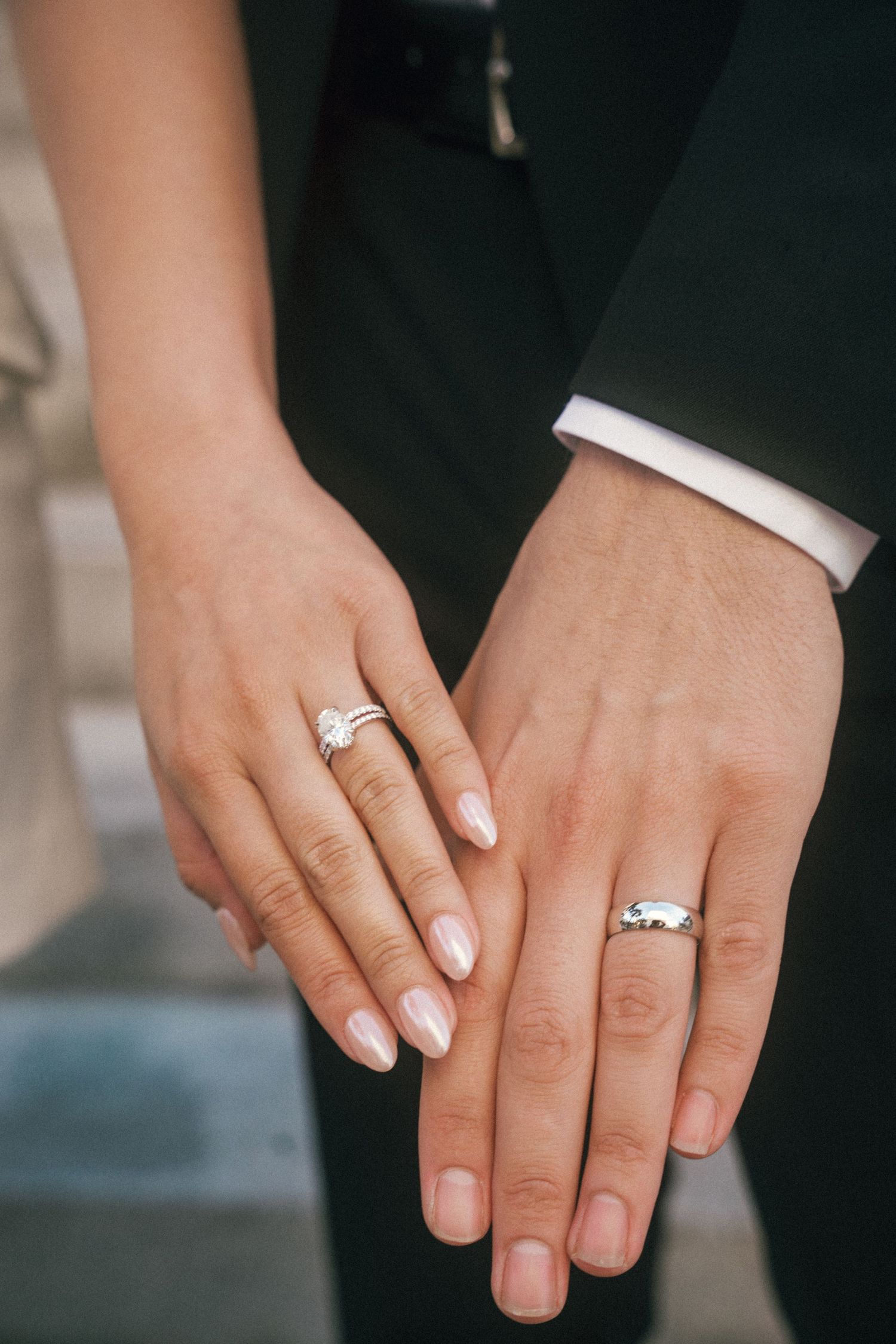 Close-up of hands showing wedding rings against formal attire.