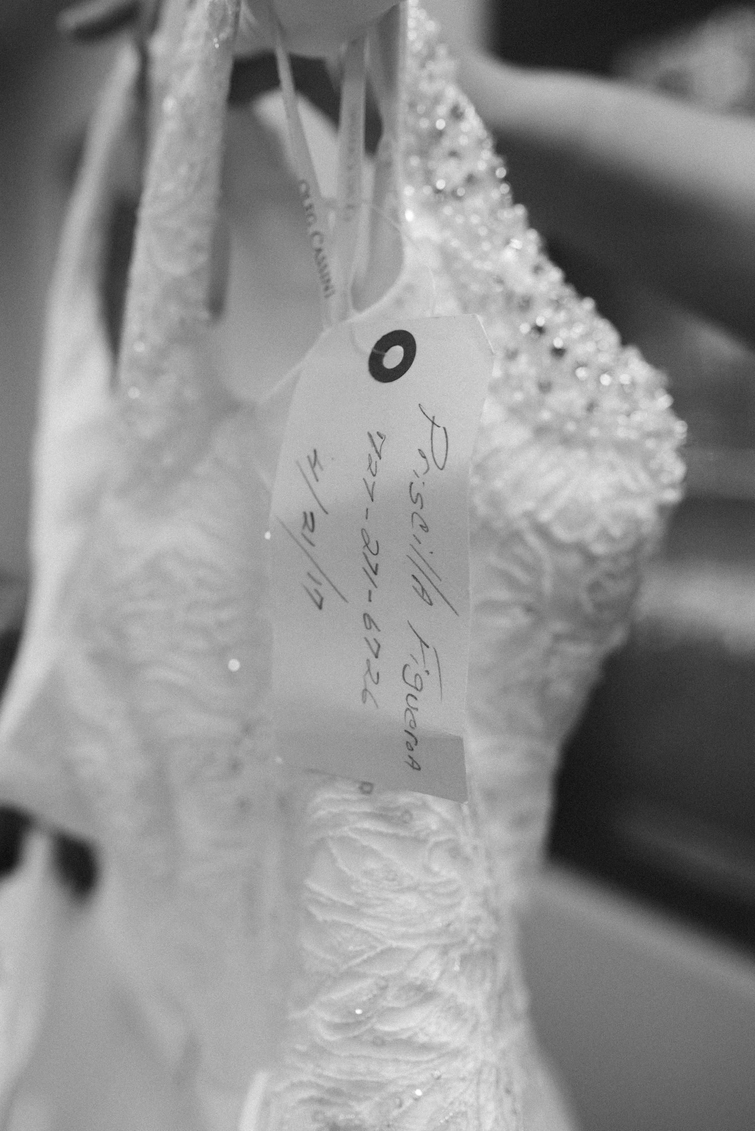 Close-up details of white wedding dresses with beaded embellishments hanging in a row.