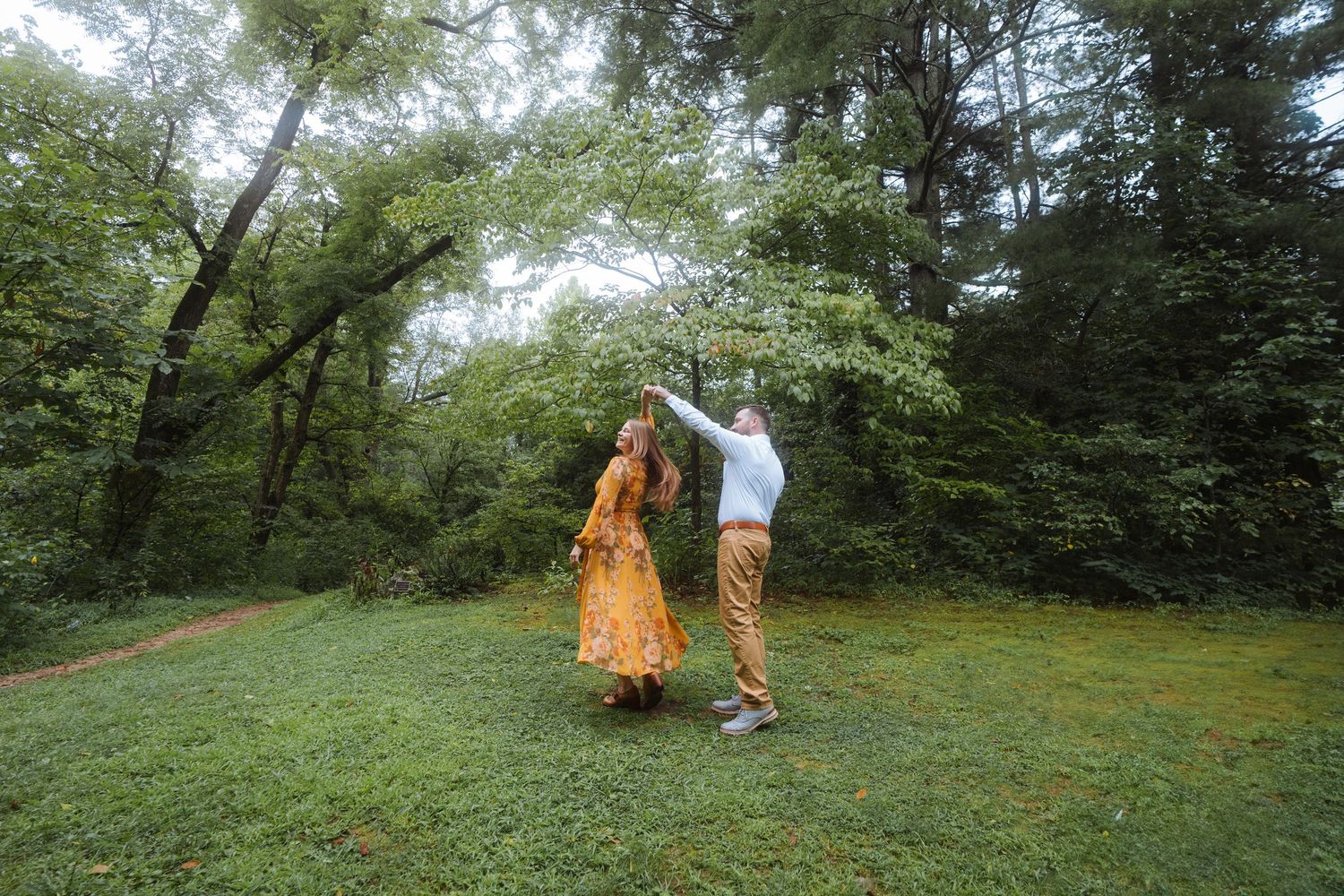 Two people share a romantic dance moment in a serene garden setting.