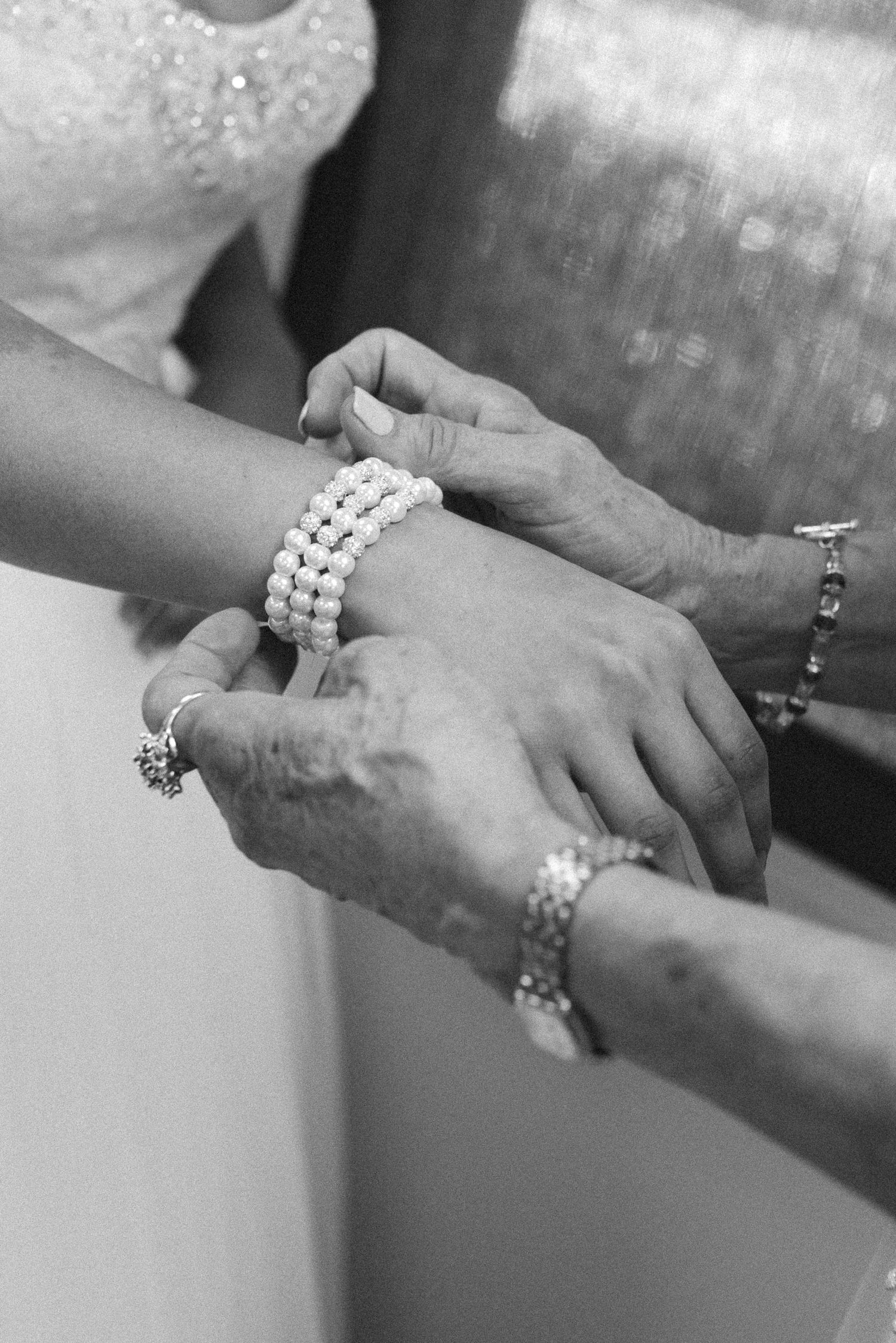 Elegant pearl bracelets and jewelry adorning hands during a wedding celebration.