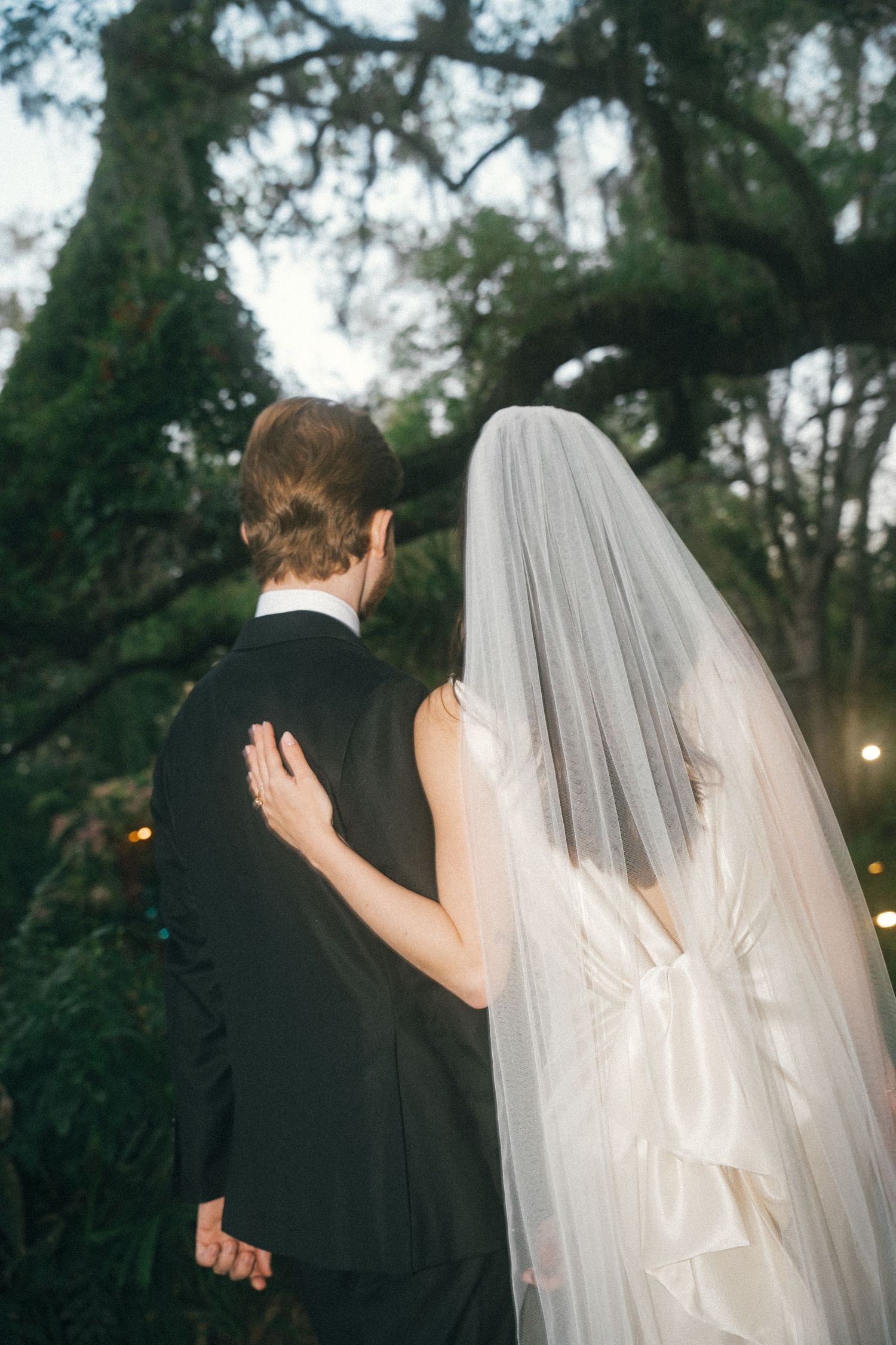 Candid wedding couple portraits captured against a backdrop of towering trees.