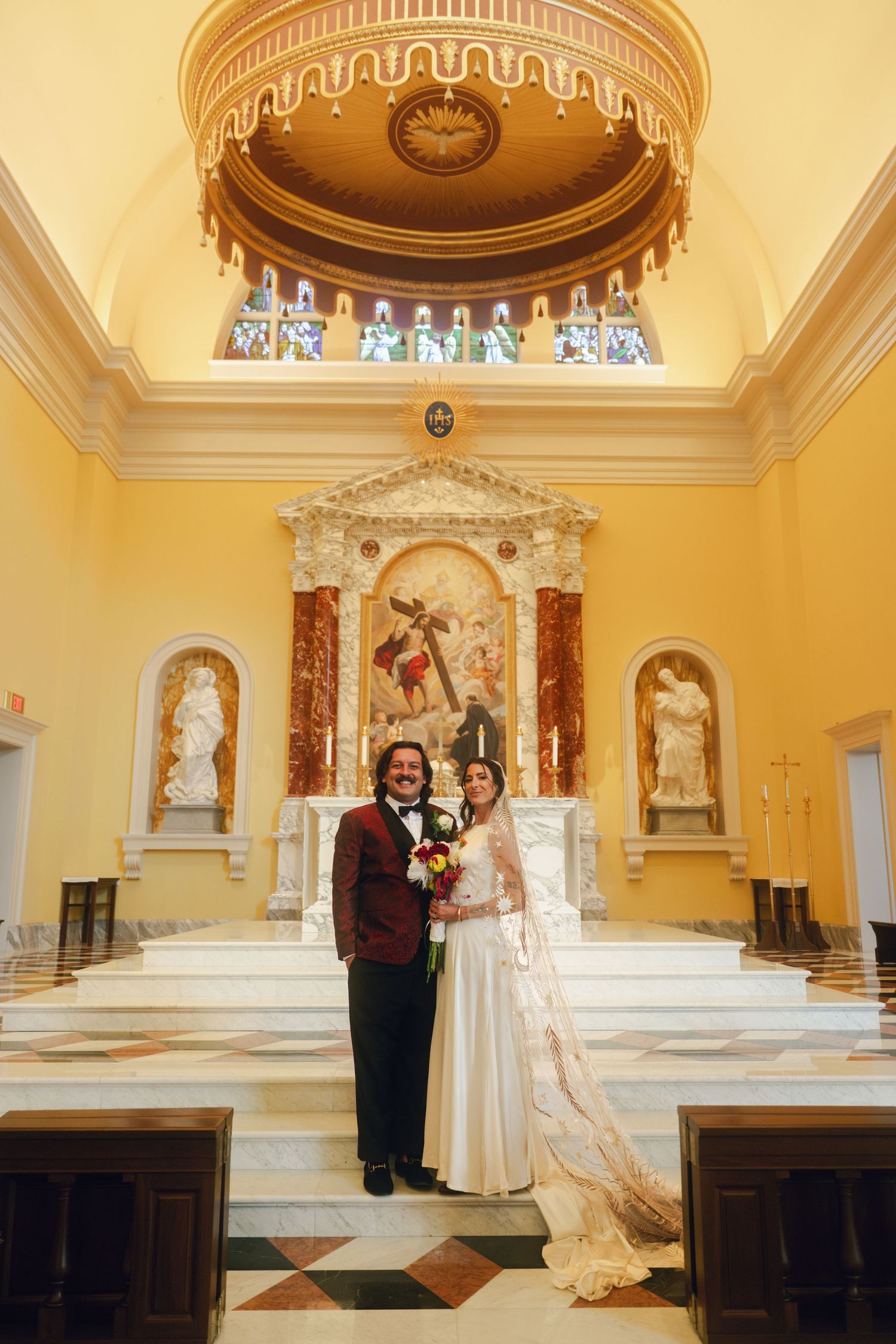 Wedding ceremony taking place in a beautiful yellow-walled church with ornate architectural details.