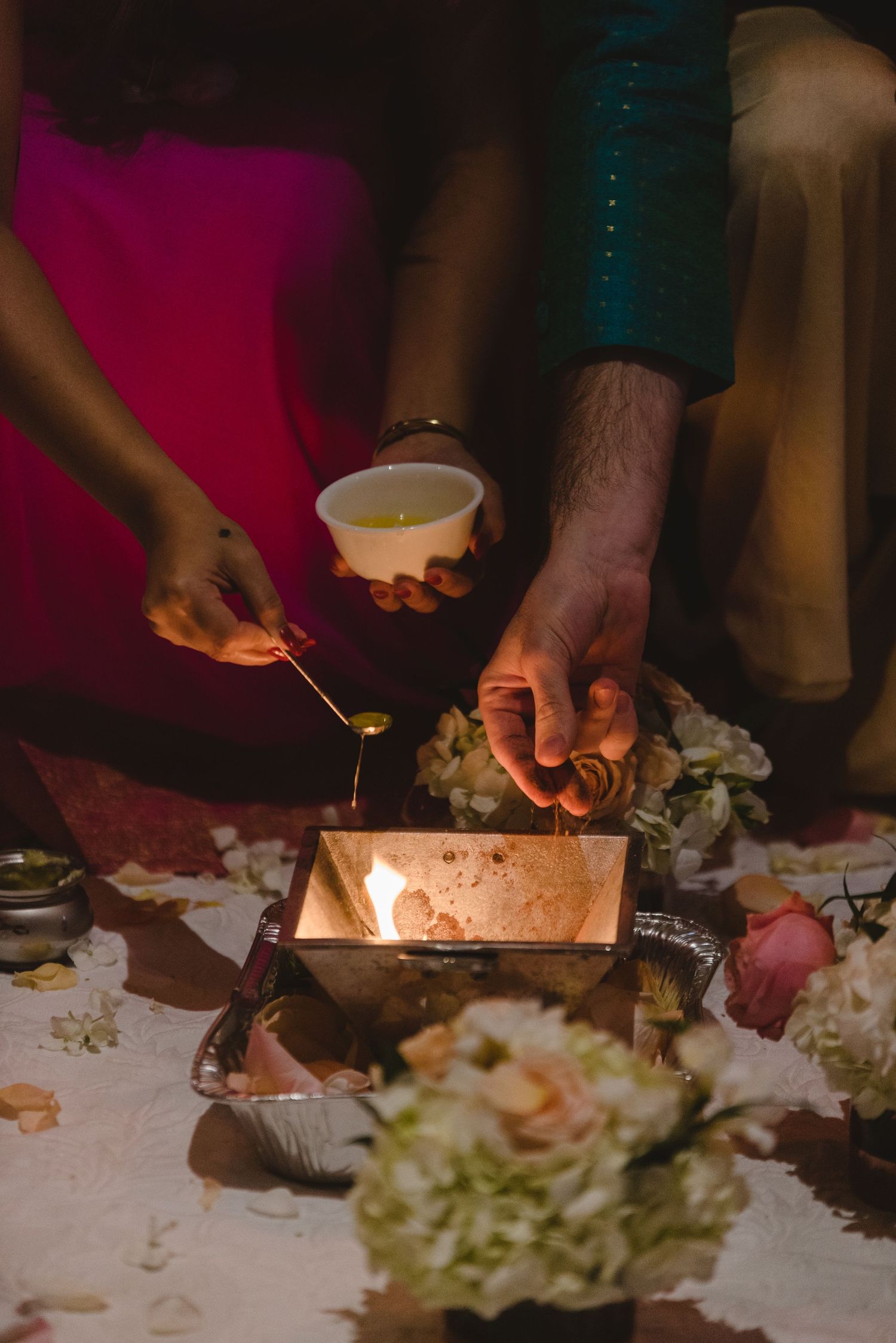 Hands lighting candles on a decorated table with white floral arrangements and linens.