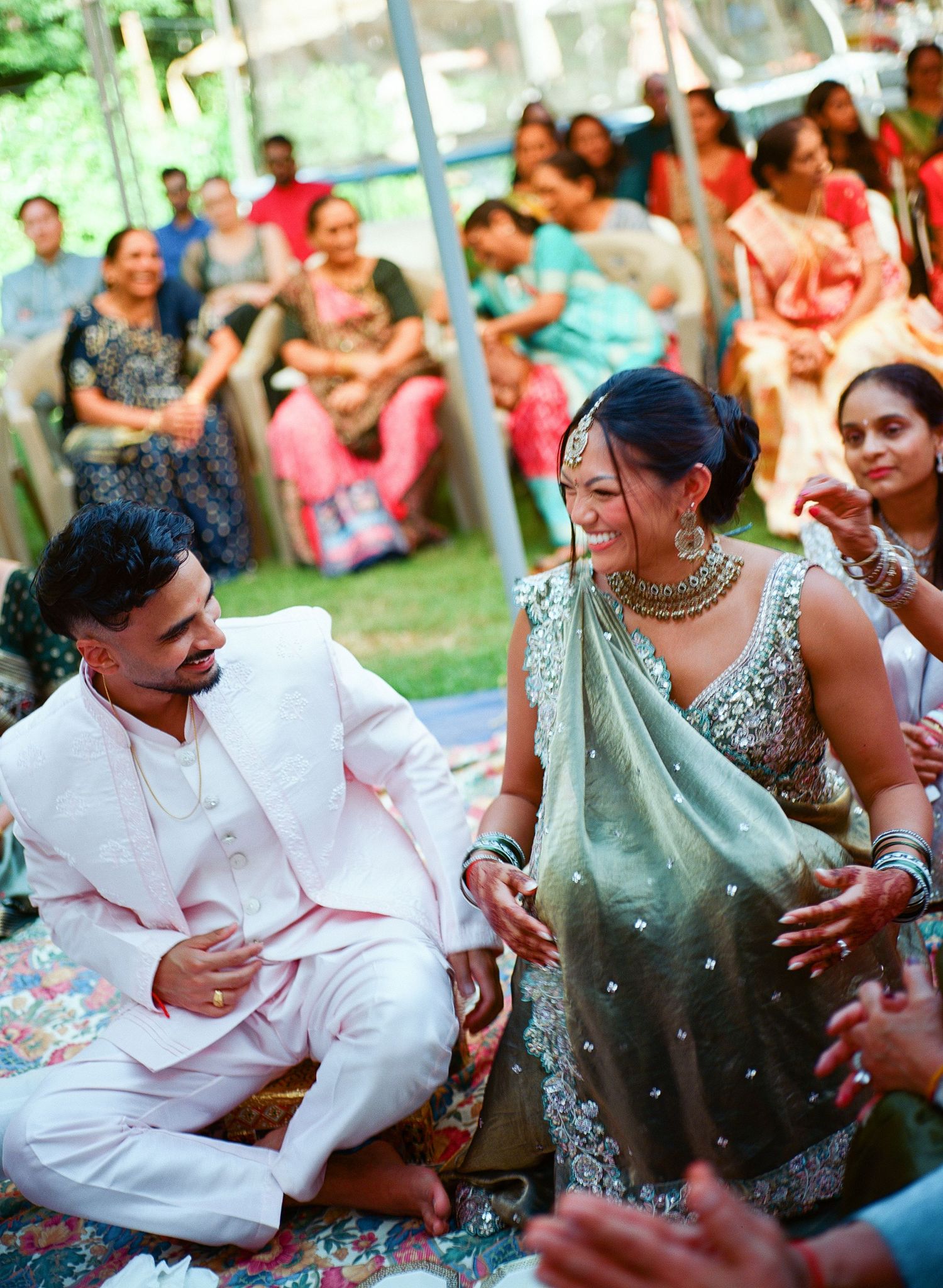 A couple shares a joyful moment during a traditional Indian celebration wearing white kurta and mint green saree.