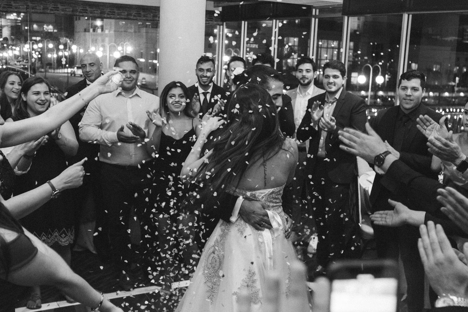 Wedding celebration with guests throwing confetti at a reception venue.