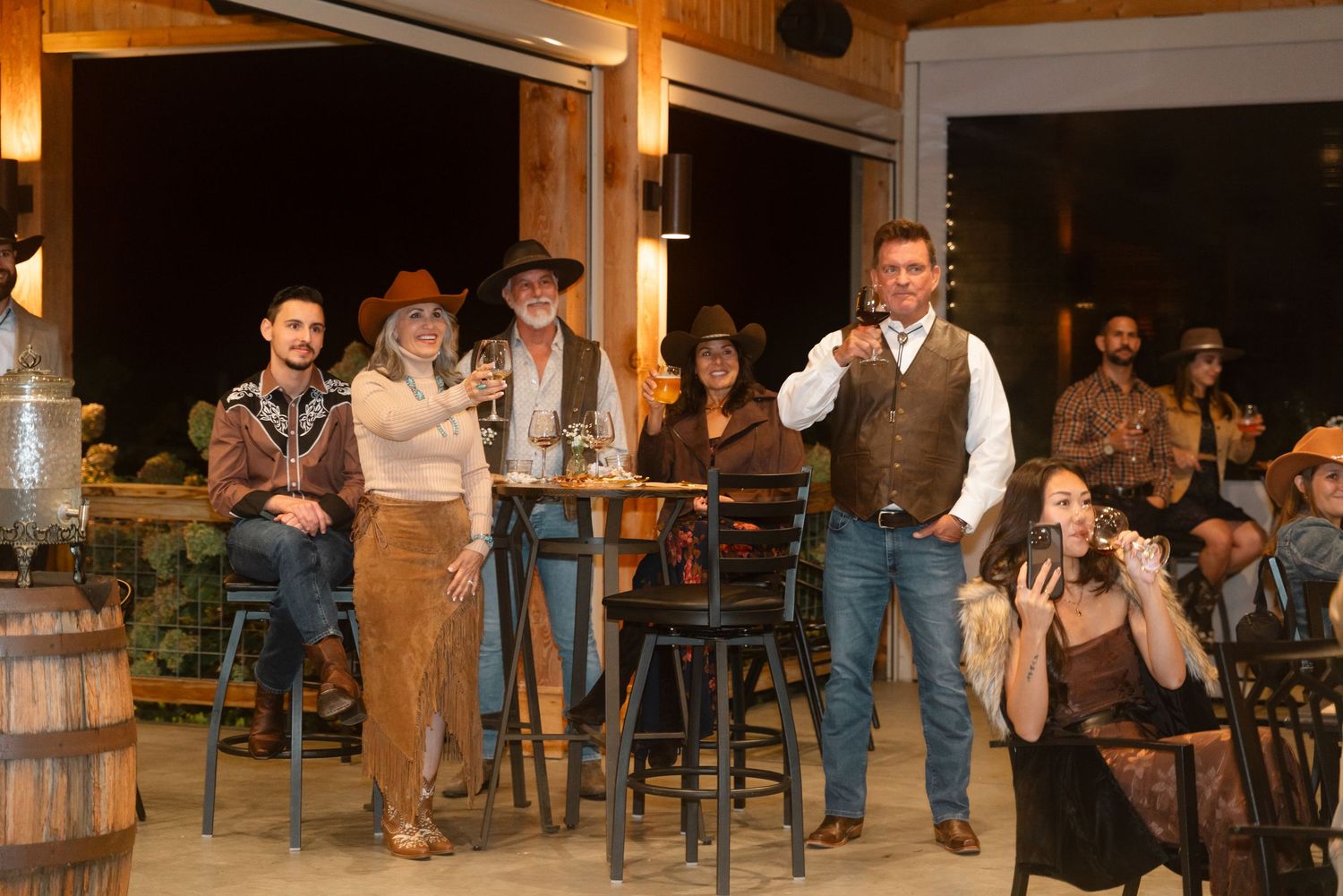 Group of people in western attire socializing at an outdoor bar venue during an evening event.